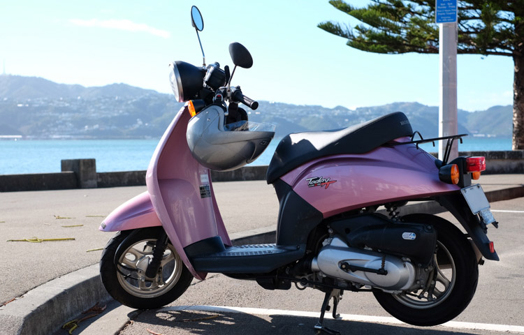 Pink moped with white helmet hanging from handlebars